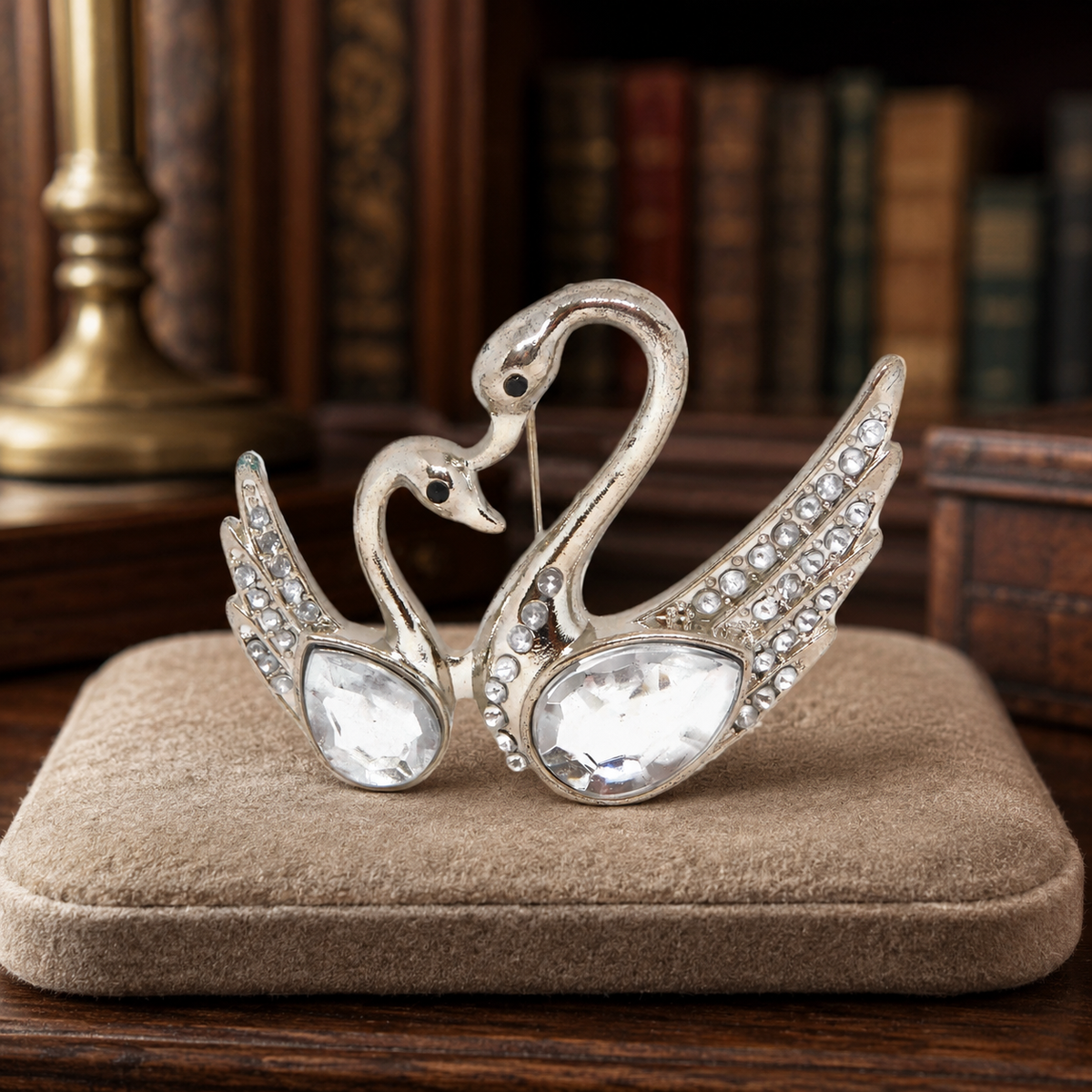 Silver-tone brooch of two swans head to head with clear rhinestone bodies and pavé wings