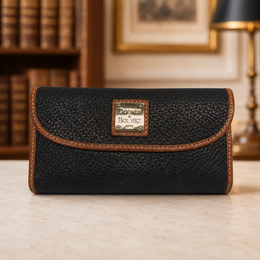 Dooney and Bourke black pebble grain leather clutch wallet with brown trim and front plaque