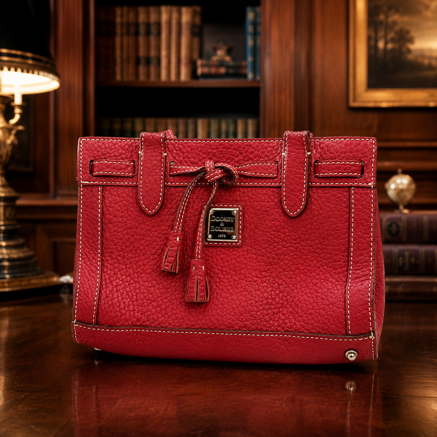 Dooney & Bourke red pebbled leather satchel with front tassel, double handles and metal feet