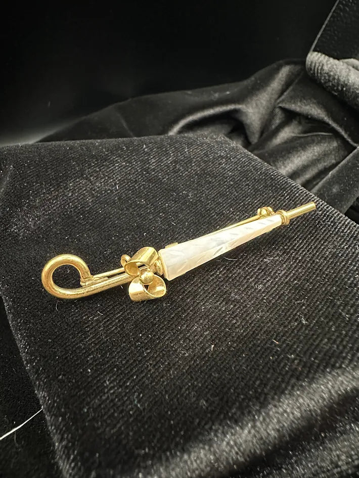 Gold tone umbrella brooch with white carved look panel and bow detail