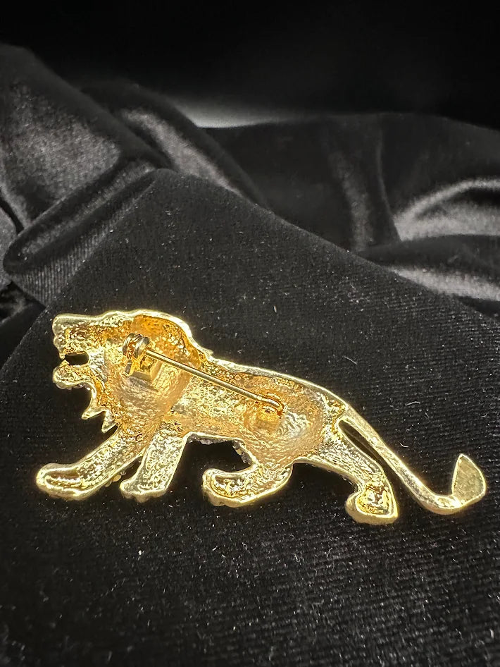 Gold tone lion brooch with clear crystals and green eye accent
