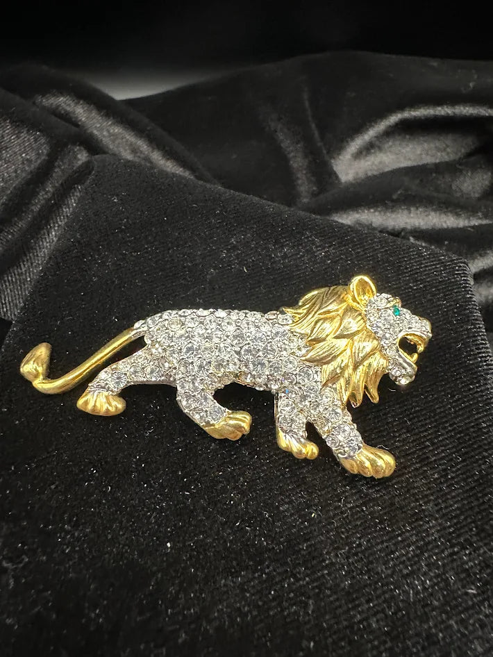 Gold tone lion brooch with clear crystals and green eye accent