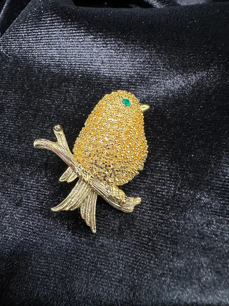 Textured gold-tone songbird brooch with green eye perched on a branch, view 3