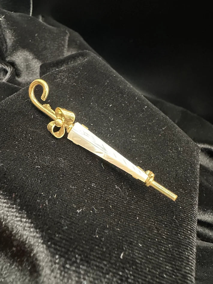 Gold tone umbrella brooch with white carved look panel and bow detail