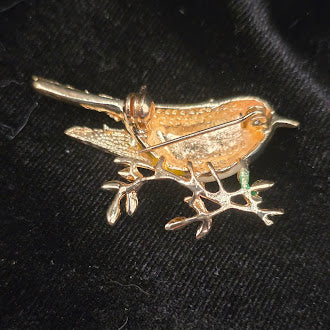 Gold-tone songbird brooch with yellow, white and black enamel on a branch with green leaves, view 3
