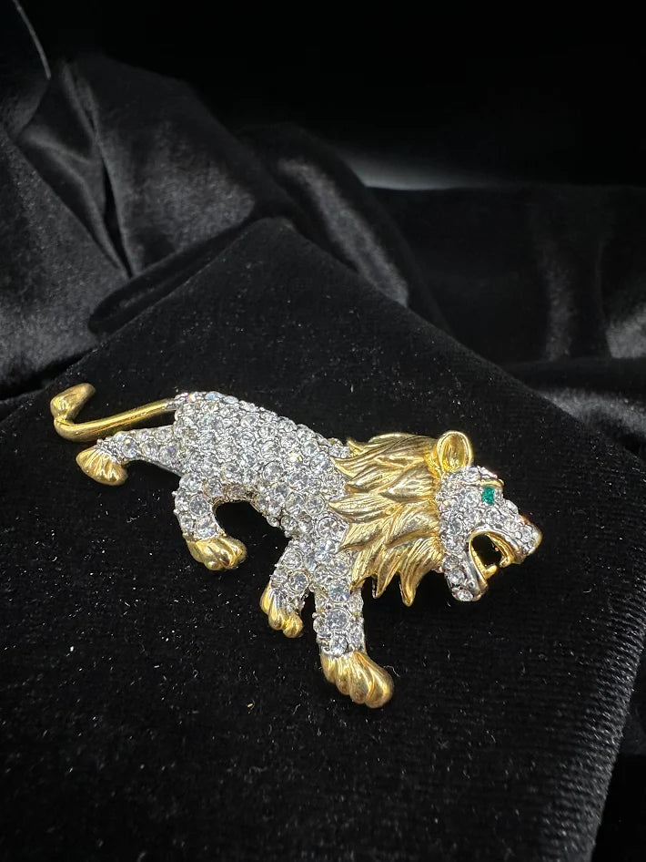 Gold tone lion brooch with clear crystals and green eye accent