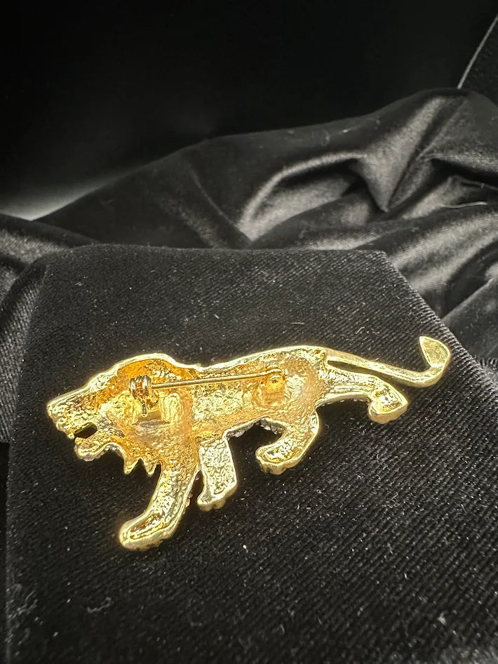 Gold tone lion brooch with clear crystals and green eye accent