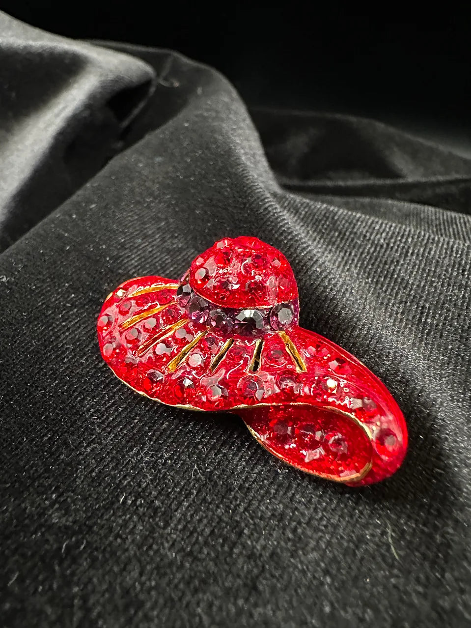 Red crystal hat brooch with curved brim, darker crystal band and gold-tone lines, view 3