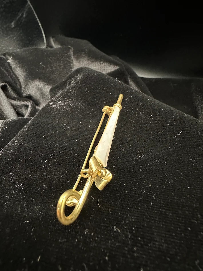 Gold tone umbrella brooch with white carved look panel and bow detail