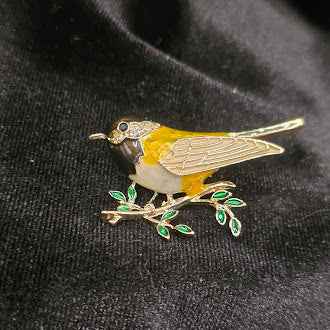 Gold-tone songbird brooch with yellow, white and black enamel on a branch with green leaves, view 4